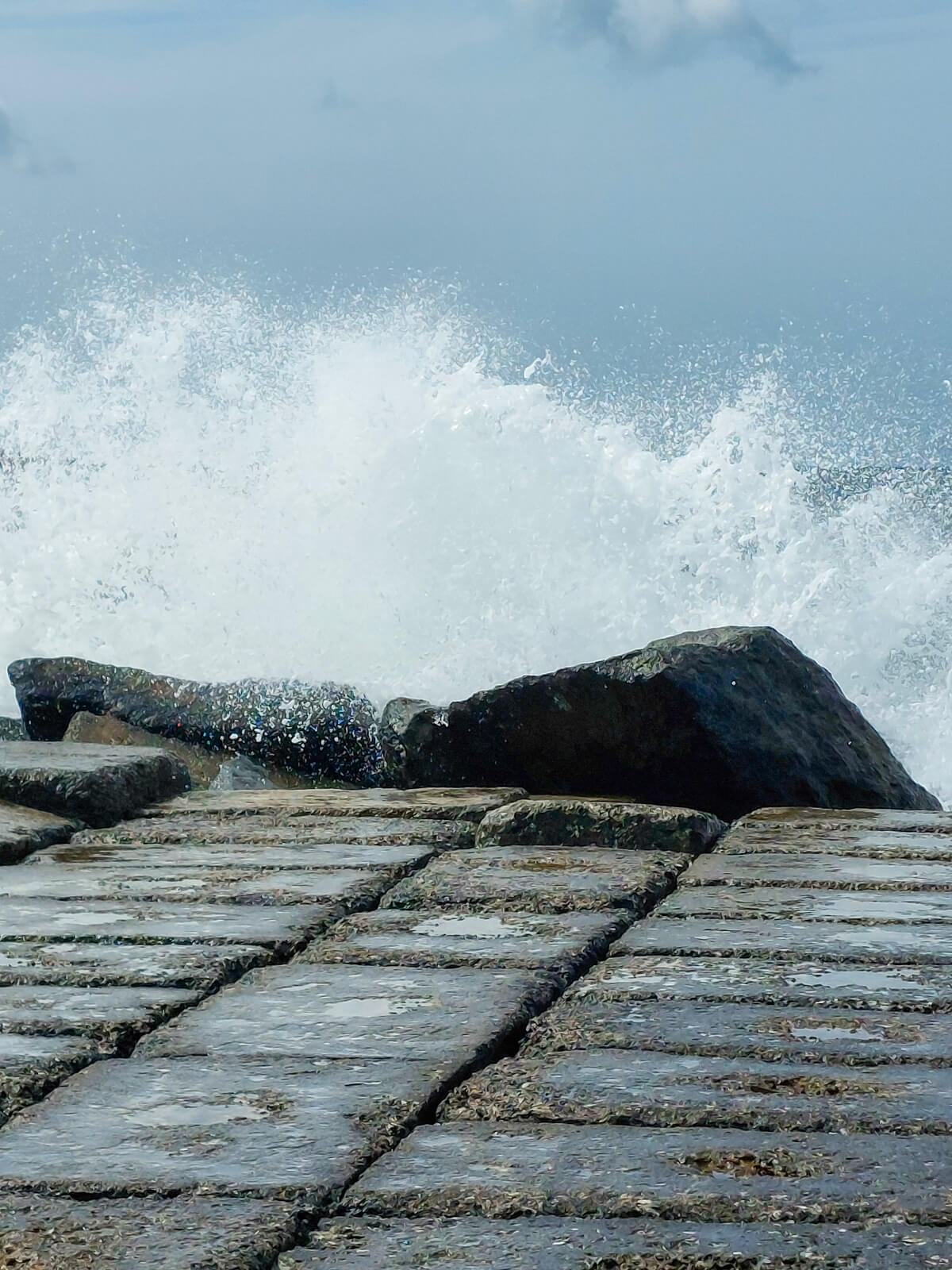 Wellen brechen kraftvoll an Felsen – Sinnbild für Widerstandskraft, Resilienz und innere Klarheit im Coaching.