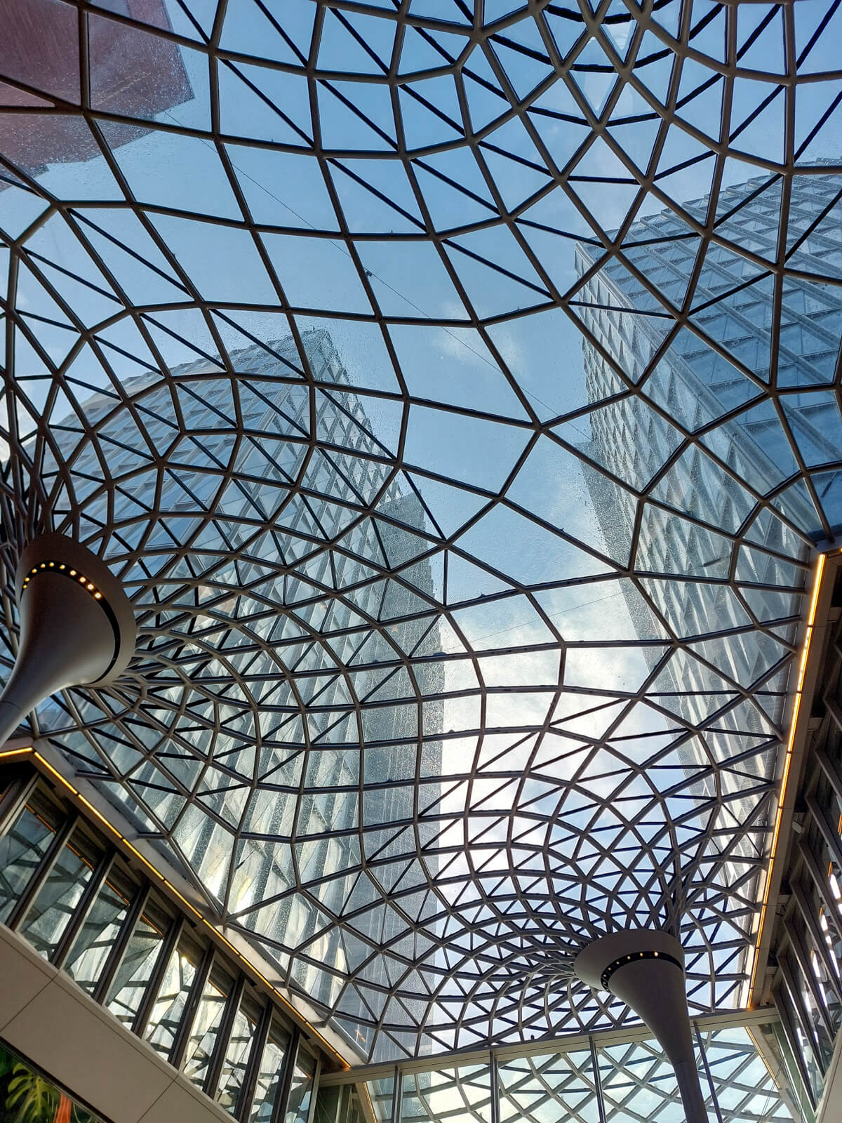 Modernes Glasdach mit geometrischen Mustern zwischen hohen Gebäuden – Sinnbild für Klarheit, Struktur und neue Perspektiven in der psychologischen Beratung.